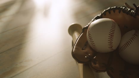 Backlit-Close-Up-Studio-Baseball-Still-Life-With-Bat-Ball-And-Catchers-Mitt-On-Aged-Wooden-Floor